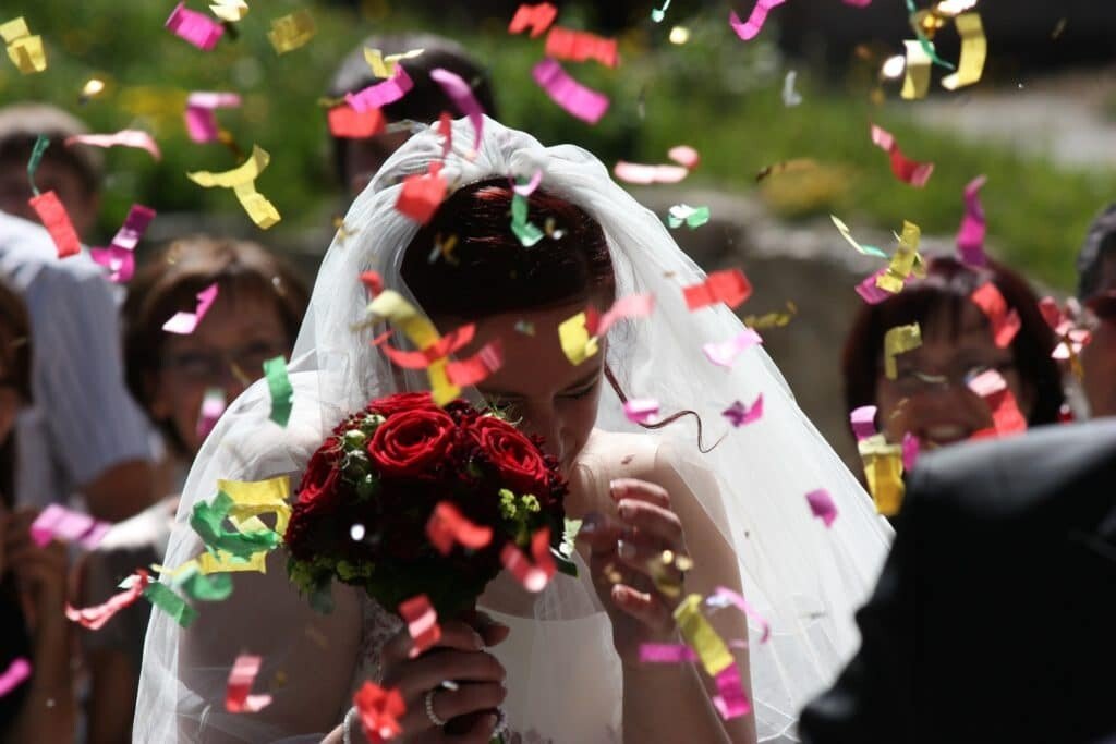 How to Choose the Perfect Wedding Venue: Bride holding her red rose bouquet with confetti around