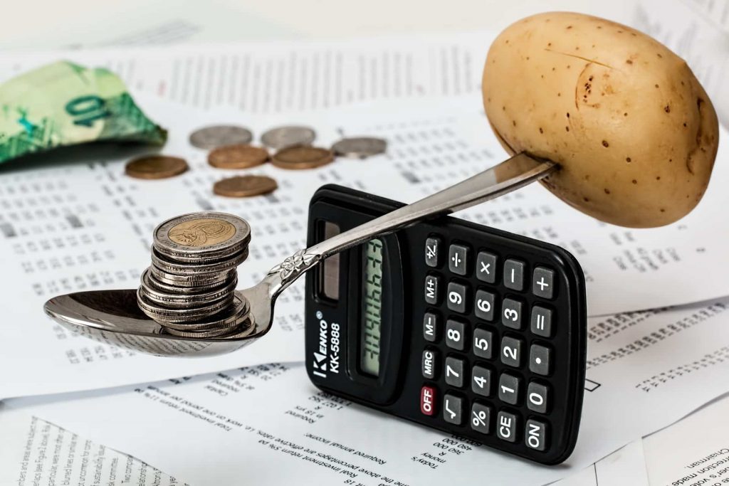 Organise your gala dinner: A photo of coins and a potato on a spoon balancing on a calculator.
