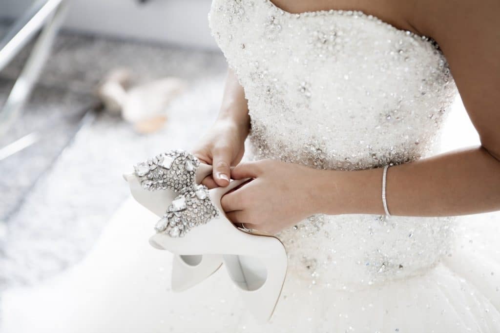 Bride holding wedding shoes white silver