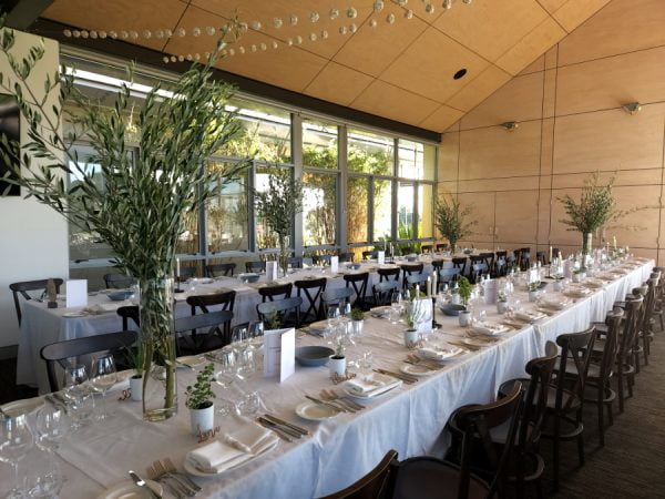 Olive branches in a tall vase on long tables