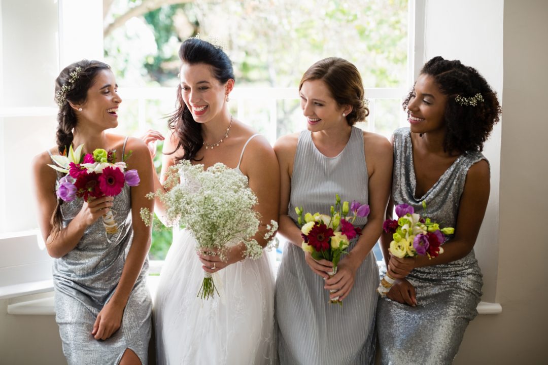 bride with bridesmaids wedding flowers smiling