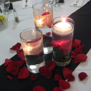 Red rose petals with candles on black