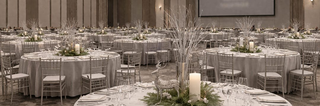 Office Christmas party table styling with silver centrepieces and festive décor. Banner 2026 corporate christmas party ideas